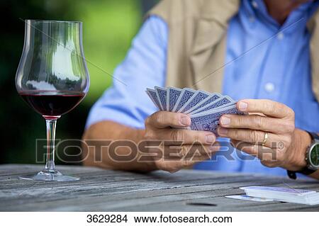 Senior man playing cards and drinking red wine, close-up View Large Photo Image Picture - Senior man playing cards and drinking red wine, close-up . Fotosearch