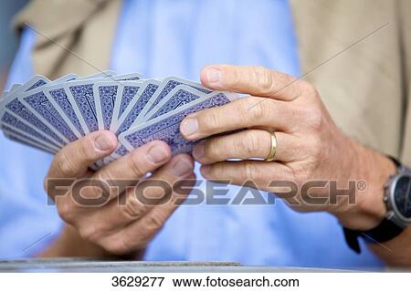 Stock Photo - Senior man playing cards, close-up . Fotosearch