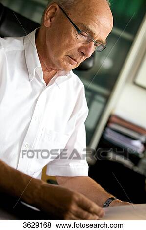 Senior man reading document at desk View Large Photo Image Stock Photo - Senior man reading document at desk . Fotosearch