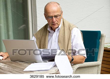 Stock Photography - Senior man using laptop on terrace . Fotosearch