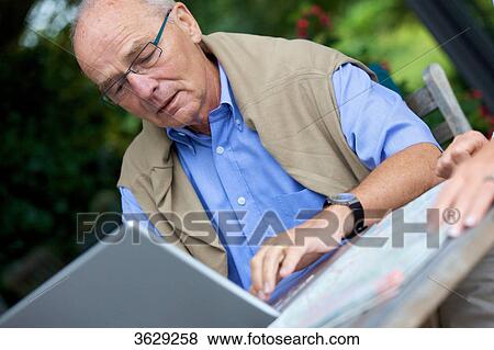 Senior man with laptop and road map, close-up View Large Photo Image Stock Photo - Senior man with laptop and road map, close-up . Fotosearch