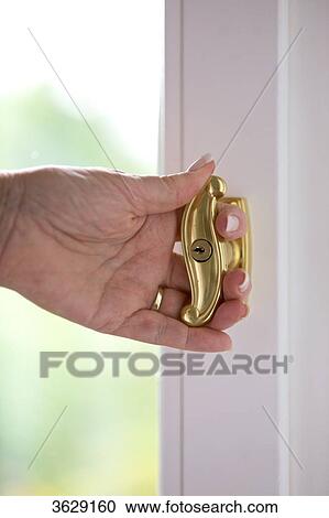 Stock Image - Senior woman opening window, close-up . Fotosearch