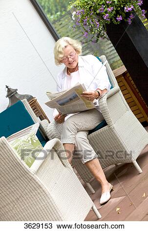 Stock Image - Senior woman reading newspaper on the terrace . Fotosearch
