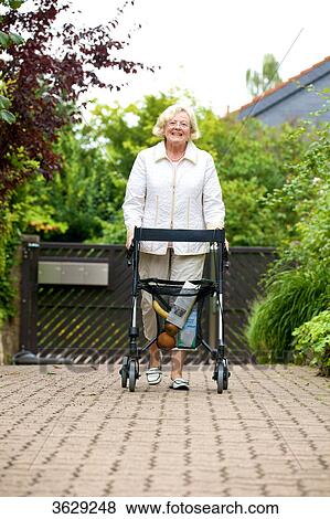 Stock Photo - Senior woman with walking frame making purchases . Fotosearch
