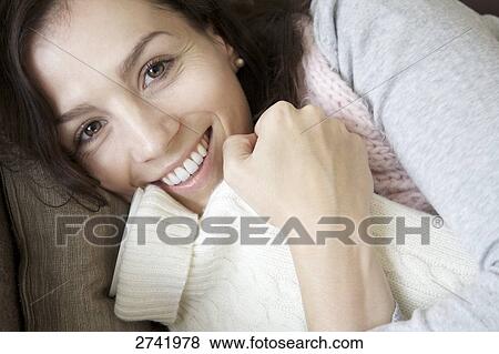 Smiling woman holding hot-waterbottle and looking at camera, elevated view View Large Photo Image Stock Photo - Smiling woman holding hot-waterbottle and looking at camera, elevated view . Fotosearch