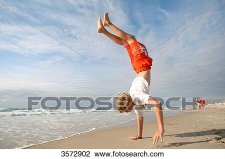 Stock Image - Teenager doing handstand at beach, Westerland, Sylt, Schleswig-Holstein, Germany, Europe . Fotosearch