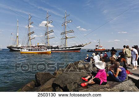Tourists sitting on rocks at coast looking at sailboats, Warnemunde, Mecklenburg-Vorpommern, Berlin, Germany View Large Photo Image Stock Image - Tourists sitting on rocks at coast looking at sailboats, Warnemunde, Mecklenburg-Vorpommern, Berlin, Germany . Fotosearch