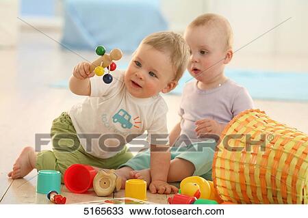 Stock Image - Two babies playing on the floor . Fotosearch