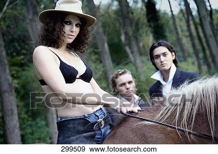 Two young men looking at young woman sitting on horse View Large Photo Image Stock Photo - Two young men looking at young woman sitting on horse . Fotosearch