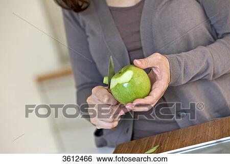 Woman peeling apple in kitchen, close-up View Large Photo Image Stock Photograph - Woman peeling apple in kitchen, close-up . Fotosearch