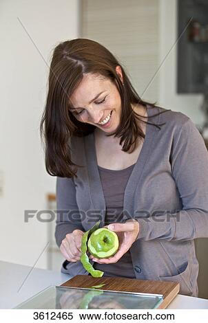 Stock Photography - Woman peeling apple in kitchen . Fotosearch