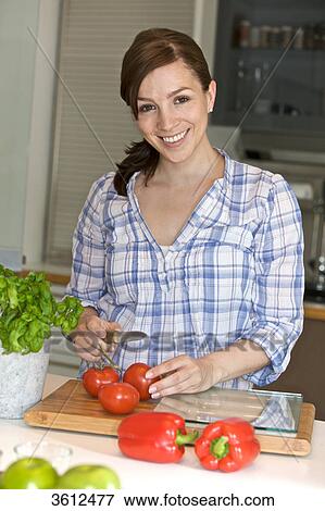 Woman slicing tomatoes in kitchen View Large Photo Image Stock Photo - Woman slicing tomatoes in kitchen . Fotosearch