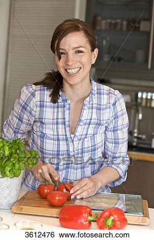 Woman slicing tomatoes in kitchen View Large Photo Image Stock Photograph - Woman slicing tomatoes in kitchen . Fotosearch