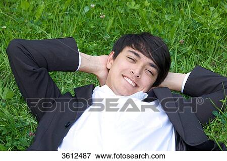 Young businessman lying in meadow View Large Photo Image Stock Photo - Young businessman lying in meadow . Fotosearch