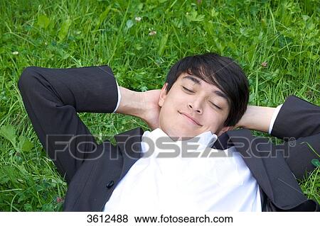 Young businessman lying in meadow View Large Photo Image Stock Photo - Young businessman lying in meadow . Fotosearch