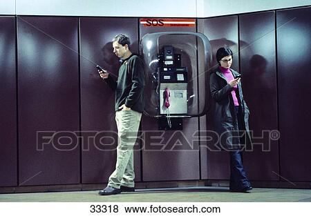 Young couple using mobile phones against telephone booth View Large Photo Image Stock Photo - Young couple using mobile phones against telephone booth . Fotosearch