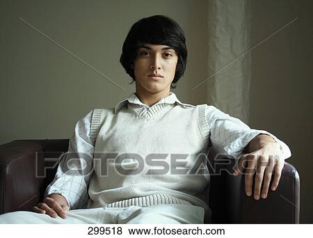 Stock Photo - Young man sitting in chair . Fotosearch