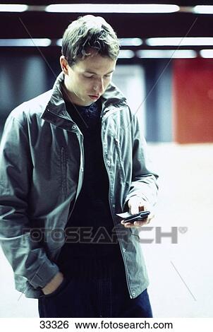 Young man using a mobile phone View Large Photo Image Stock Photograph - Young man using a mobile phone . Fotosearch