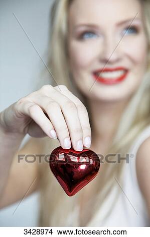 Young woman holding a heart, portrait View Large Photo Image Picture - Young woman holding a heart, portrait . Fotosearch