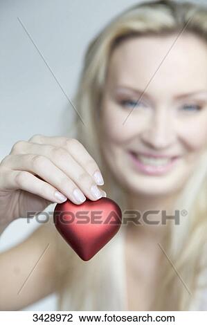 Stock Image - Young woman holding a heart, portrait . Fotosearch