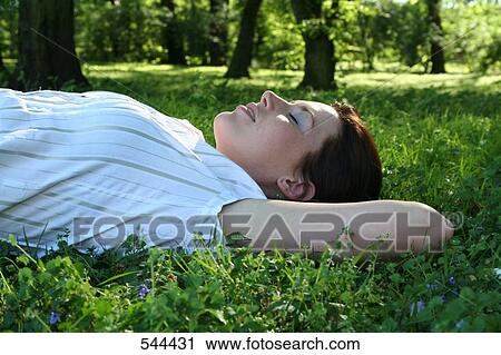 Young woman lying on meadow, side view View Large Photo Image Stock Image - Young woman lying on meadow, side view . Fotosearch