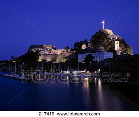 Stock Photo - Boats moored at harbor lit up at night . Fotosearch