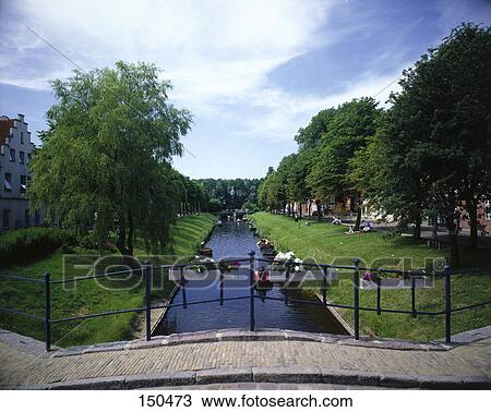 Stock Image - Bridge across canal with boats in background . Fotosearch