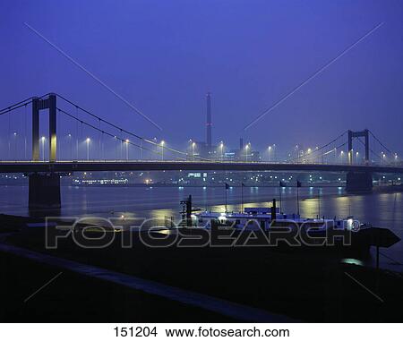 Bridge across river lit up at dusk, Duisburg, North Rhine-Westphalia, Germany View Large Photo Image Picture - Bridge across river lit up at dusk, Duisburg, North Rhine-Westphalia, Germany . Fotosearch