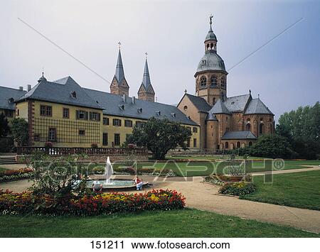 Stock Image - Children at water fountain in front of cathedral, Seligenstadt, Hesse, Germany . Fotosearch