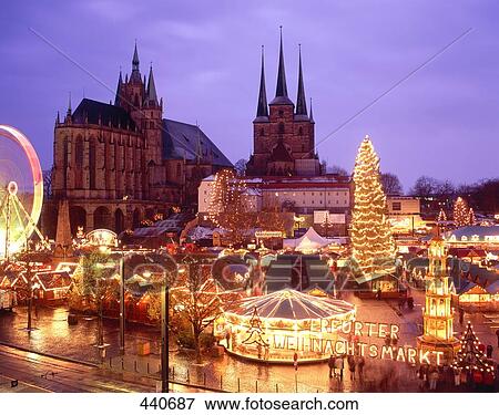 Stock Photo - Christmas fair lit up at dusk in front of church . Fotosearch