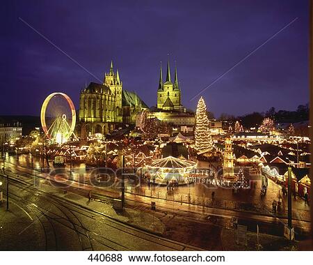 Stock Photo - Christmas fair lit up at dusk in front of church . Fotosearch