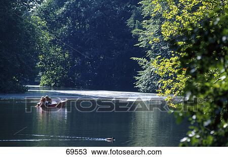 Stock Image - Couple romancing in boat in lake . Fotosearch