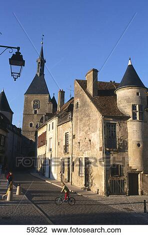 Stock Image - Girl cycling in street, old part of town, Avallon, Burgundy, France . Fotosearch