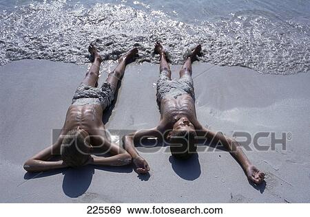 Stock Photo - High angle view of two boys lying on beach . Fotosearch