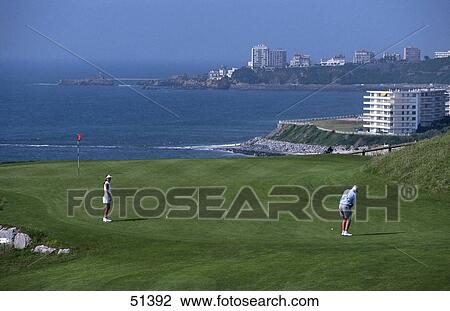 Stock Image - High angle view of two people playing golf on golf course, Biarritz, France . Fotosearch