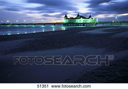 Stock Image - House lit up at dawn on beach, Ahlbeck Pier, Usedom Island, Germany . Fotosearch