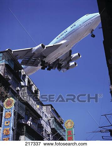 Low angle view of airplane flying over building, China View Large Photo Image Stock Photo - Low angle view of airplane flying over building, China . Fotosearch