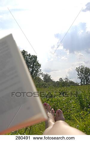 Stock Image - Low section view of woman relaxing in a field . Fotosearch