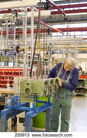 Stock Image - Man checking pumps in production plant, Baden-Wuerttemberg, Germany . Fotosearch