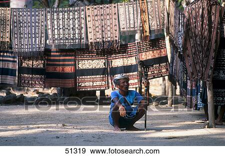 Stock Photo - Man crouching in front of Ikat cloths, Sawu Island, Indonesia . Fotosearch