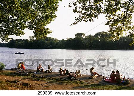 Stock Photo - People relaxing on pier at riverside, Hannover, Lower Saxony, Germany . Fotosearch