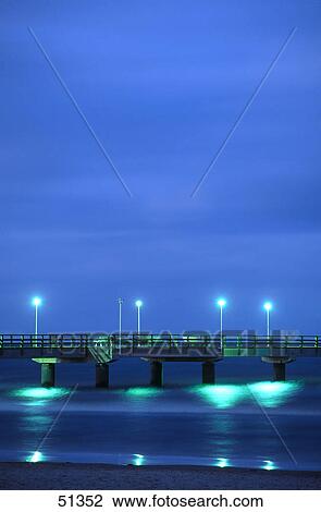 Stock Image - Pier lit up at dawn on beach, Ahlbeck Pier, Usedom Island, Germany . Fotosearch