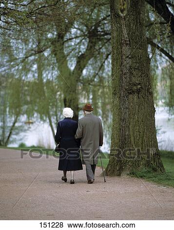Stock Photo - Rear view of senior couple walking in park . Fotosearch