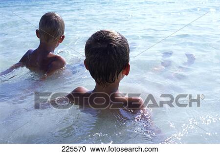 Rear view of two boys in water View Large Photo Image Stock Image - Rear view of two boys in water . Fotosearch