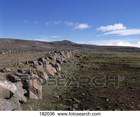 Stock Photograph - Rocks on arid landscape under blue sky, Funchal, Madeira Island, Portugal . Fotosearch