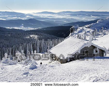 Stock Image - Snow covered wooden cabin on landscape viewed from Great Arber mountain, Bavarian Forest National Park, Bavaria, Germany . Fotosearch