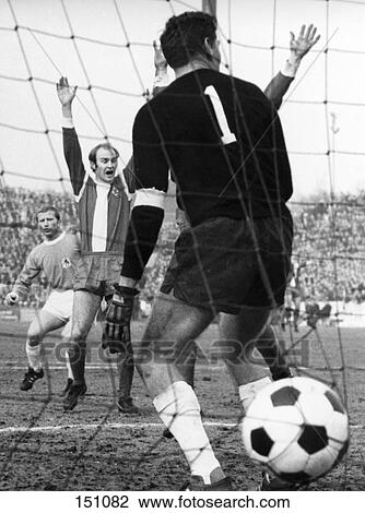 Soccer ball in net with referee raising hands in background, Germany View Large Photo Image Stock Image - Soccer ball in net with referee raising hands in background, Germany . Fotosearch