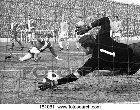 Stock Image - Soccer goalkeeper diving to save ball in stadium, Germany . Fotosearch