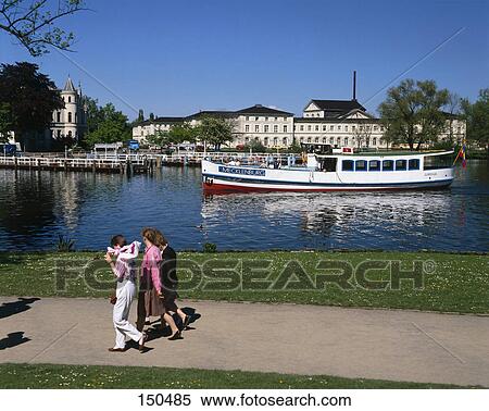 Stock Photography - Three people walking along river, Schwerin, Germany . Fotosearch