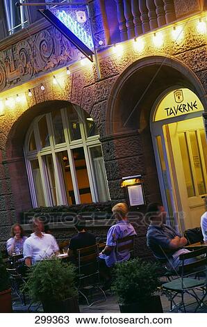 Stock Image - Tourists sitting at sidewalk cafe, Taverne Odyssia, Stuttgart, Baden-Wurttemberg, Germany . Fotosearch